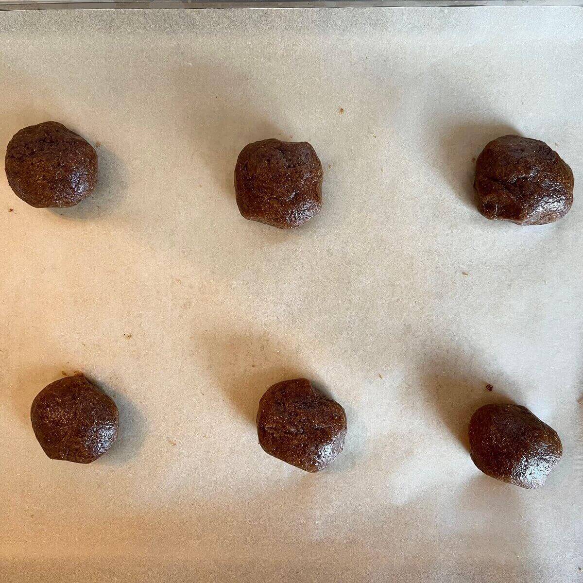 Flax cookie dough balls on a sheet pan lined with parchment paper.