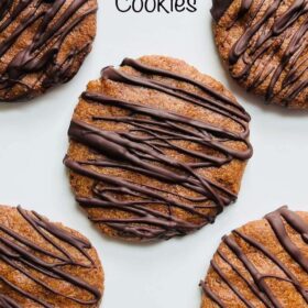 Cookies drizzled with dark chocolate on a white plate.