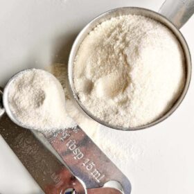 A measuring cup and measuring spoon filled with coconut flour.