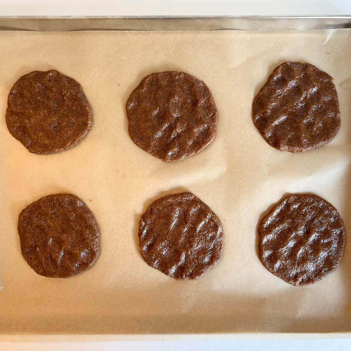 Raw flax cookies on a sheet pan lined with parchment paper.