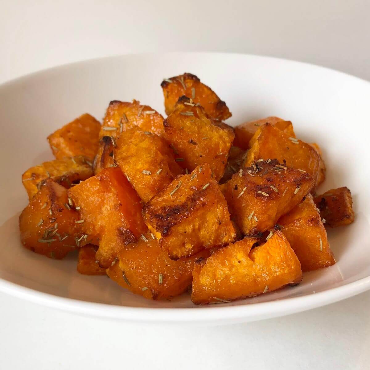 Roasted squash in a white serving bowl.