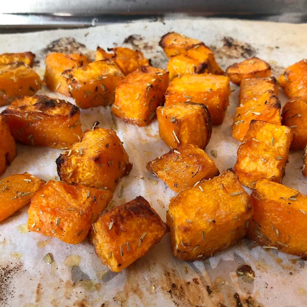Roasted sweet potatoes on a baking tray lined with parchment paper.