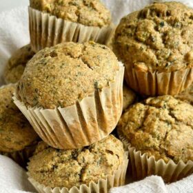Muffins piled in a basket lined with a linen napkin.