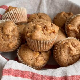 A cloth-lined basket full of freshly baked muffins.