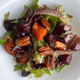 Salad piled high in a white bowl.