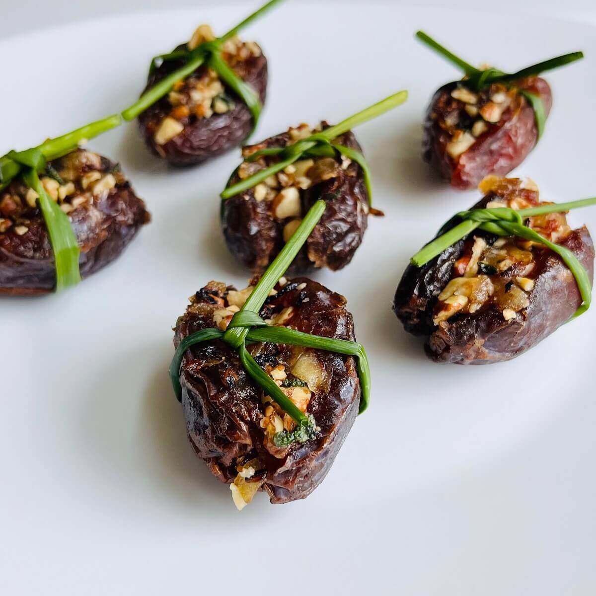Date appetizers tied with a fresh chive.