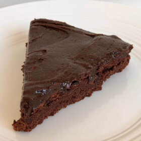 A slice of chocolate coconut flour cake on a white plate.