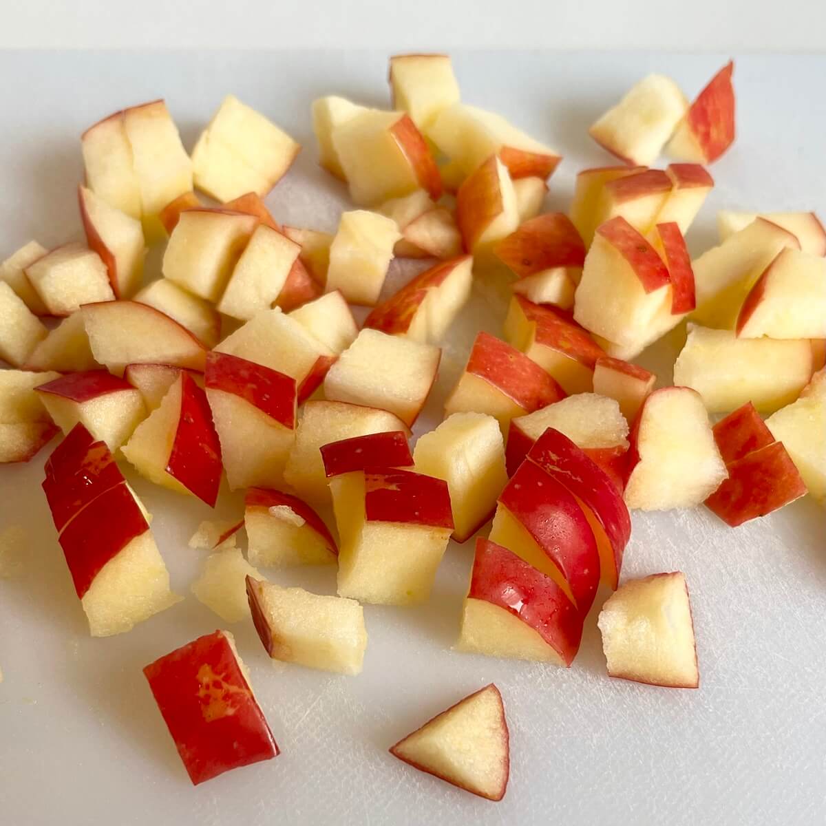 Chopped Honeycrisp apples on a white cutting board.