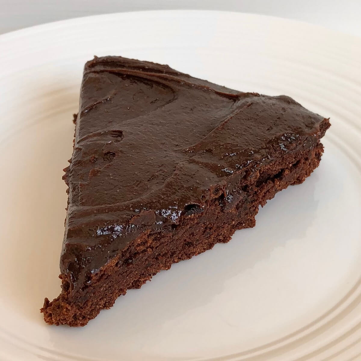 A slice of chocolate cake made with coconut flour on a white plate.