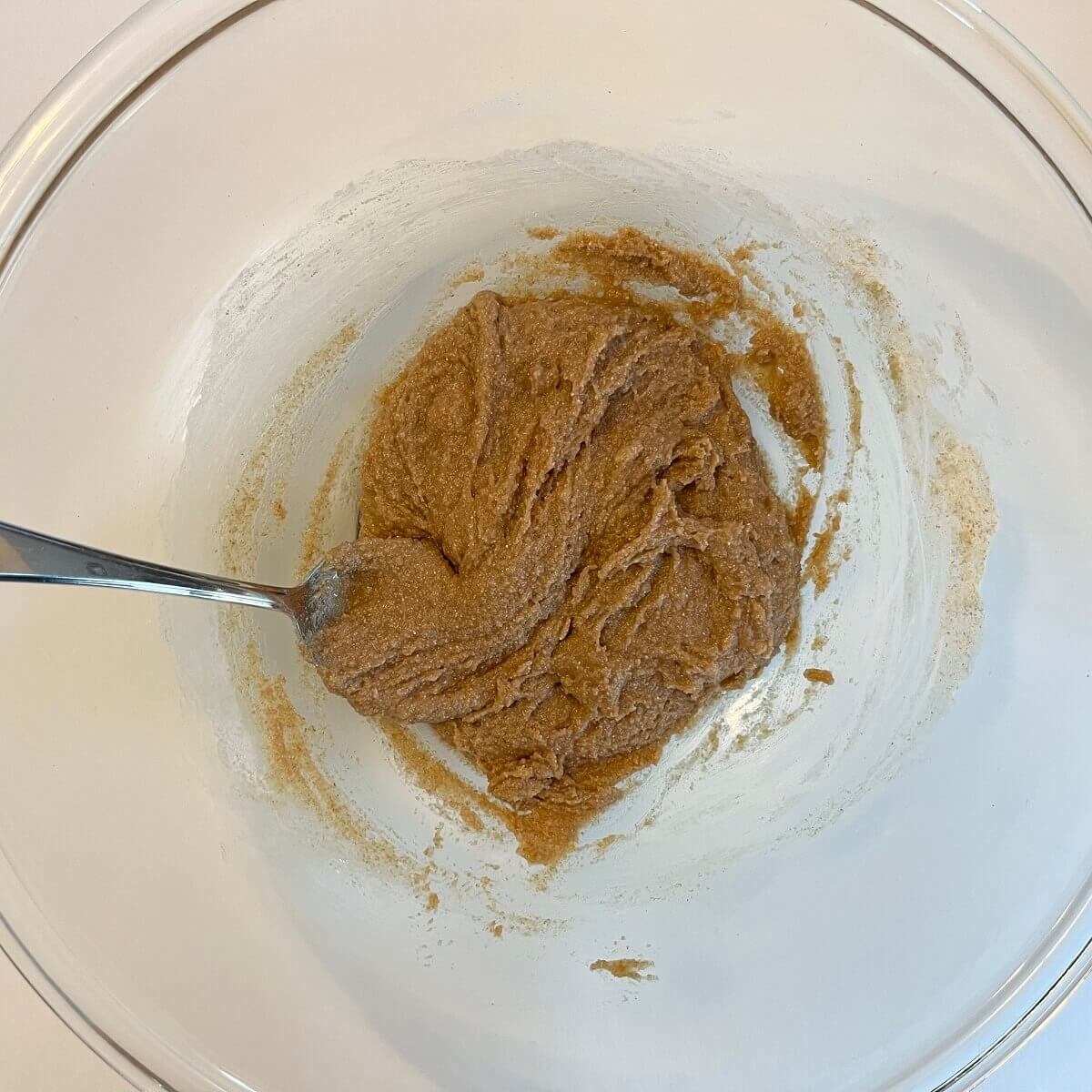 Thick cookie dough in a large glass mixing bowl.