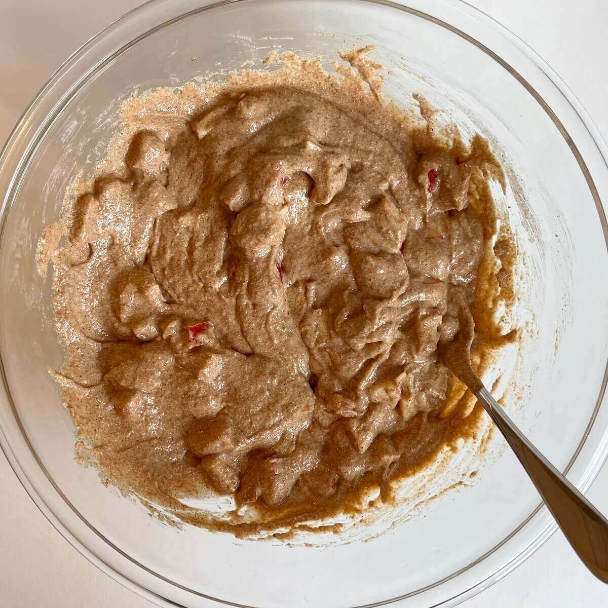 A bowl of apple muffin batter with a spoon.