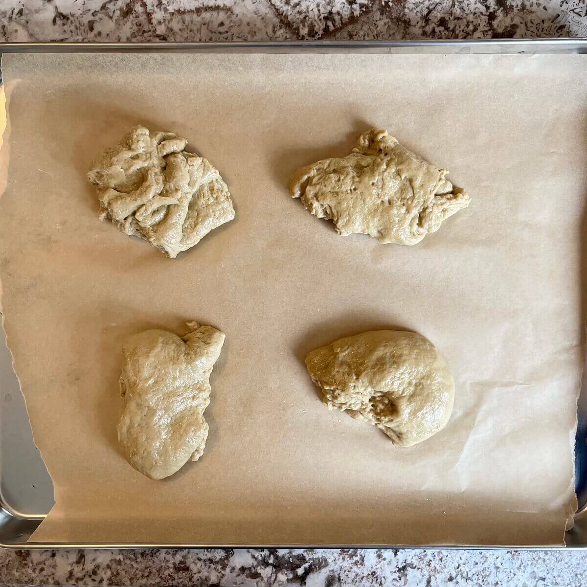 Four pieces of raw vegan chicken on a sheet pan lined with parchment paper.