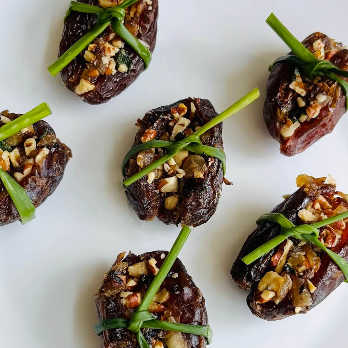 Pecan stuffed dates on a white plate.