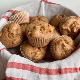 Vegan apple muffins in a basket lined with a red striped towel.