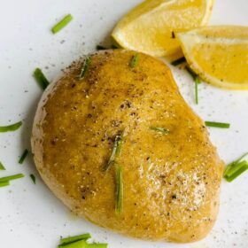 Plant-based chicken on a white plate next to two lemon wedges.