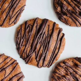 Cookies drizzled with melted chocolate on a white platter.