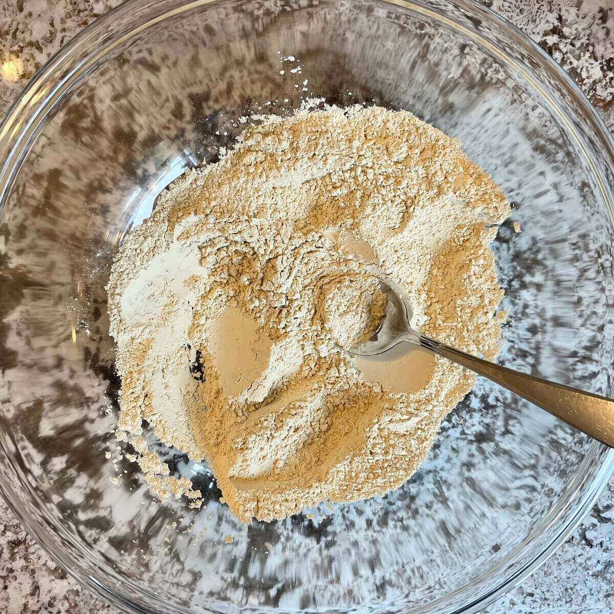 Vital wheat gluten and other dry ingredients in a large glass mixing bowl.