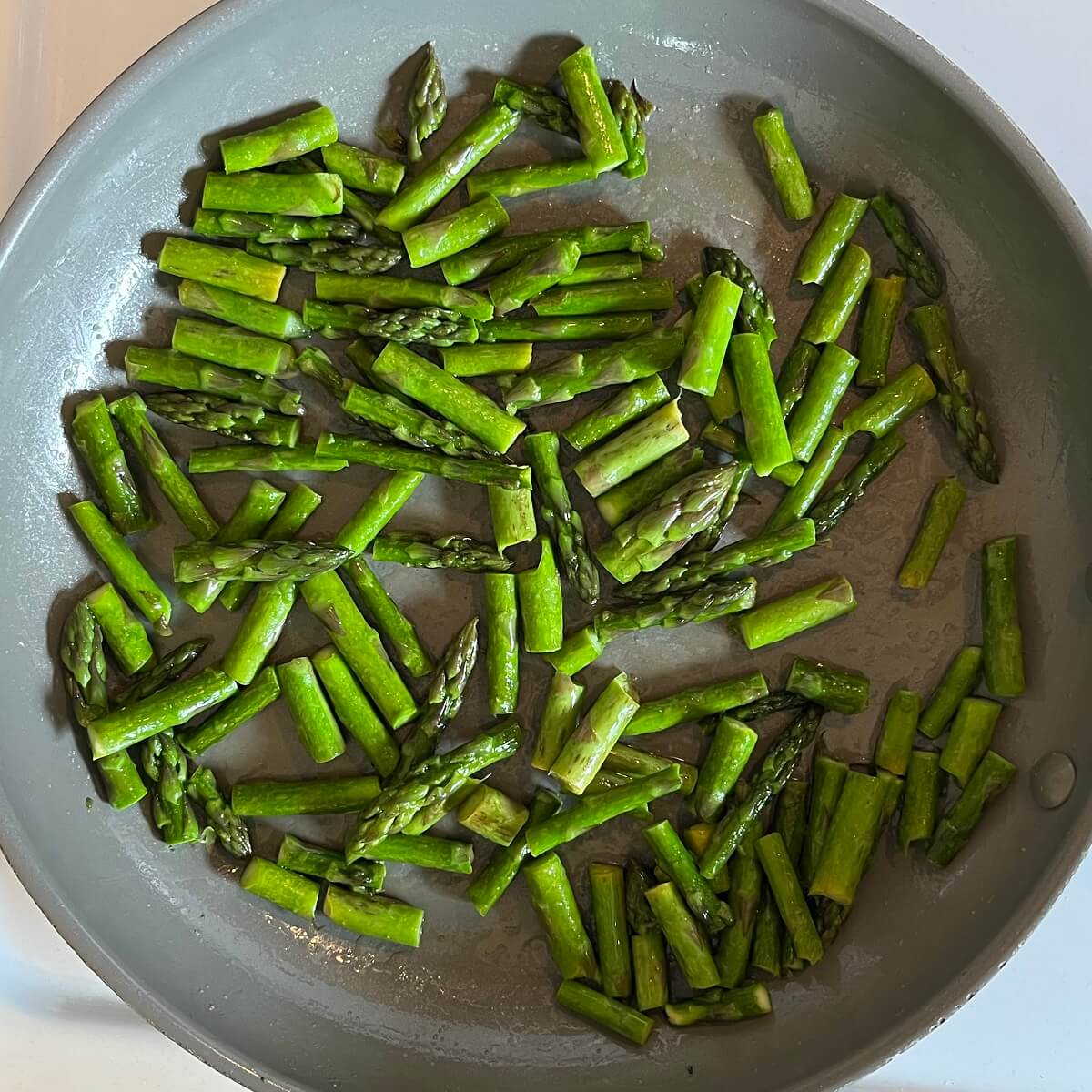 Chopped asparagus in a frying pan.