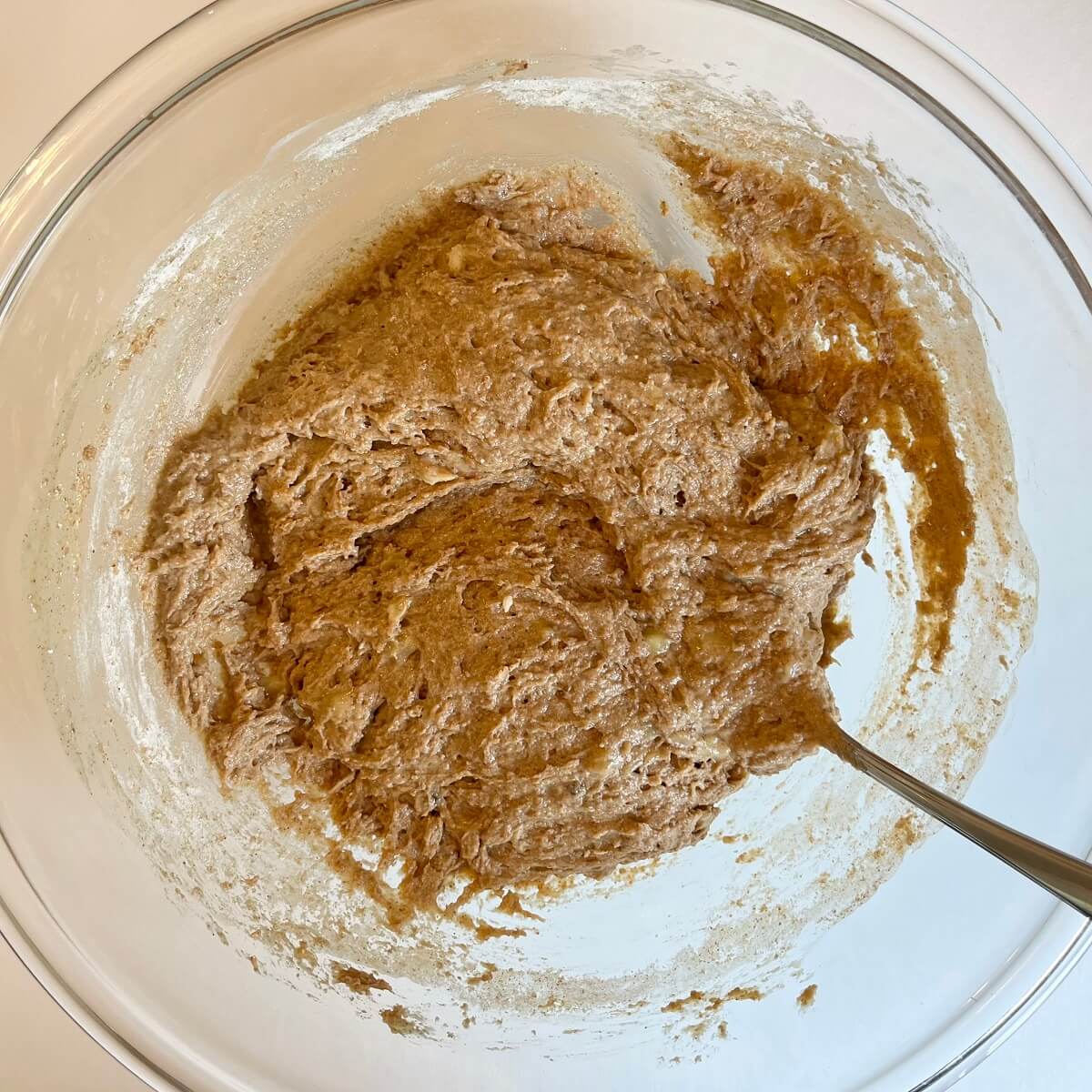 Muffin batter being stirred in a large glass bowl.