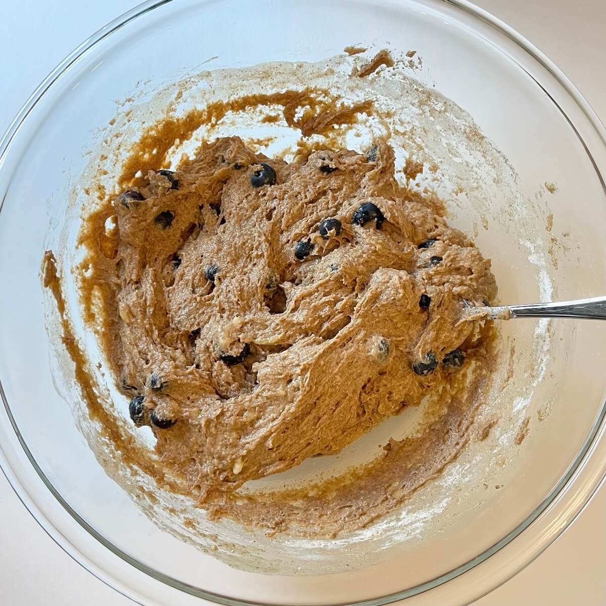 Blueberry muffin batter in a glass mixing bowl.