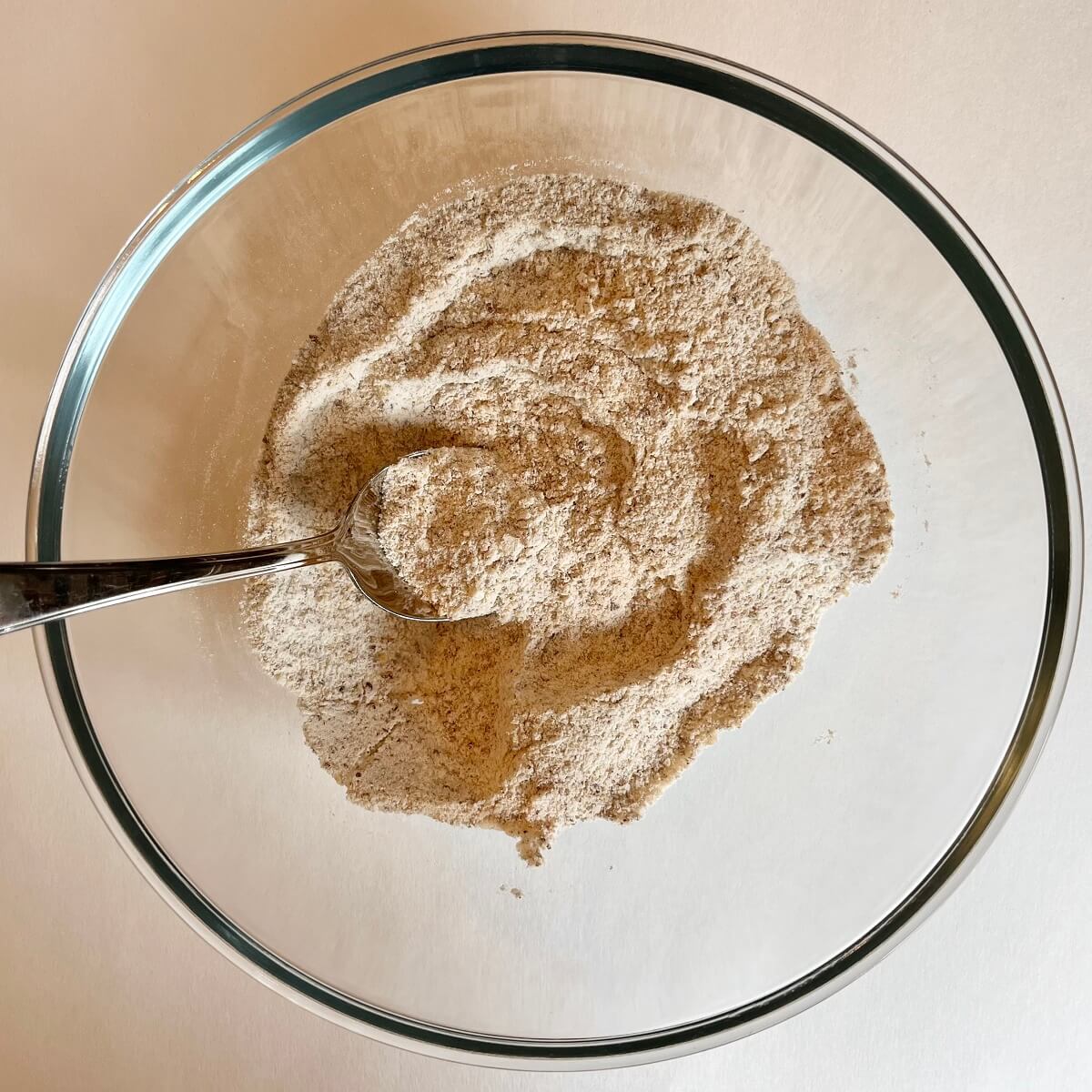 Dry ingredients for carrot cake in a glass mixing bowl.