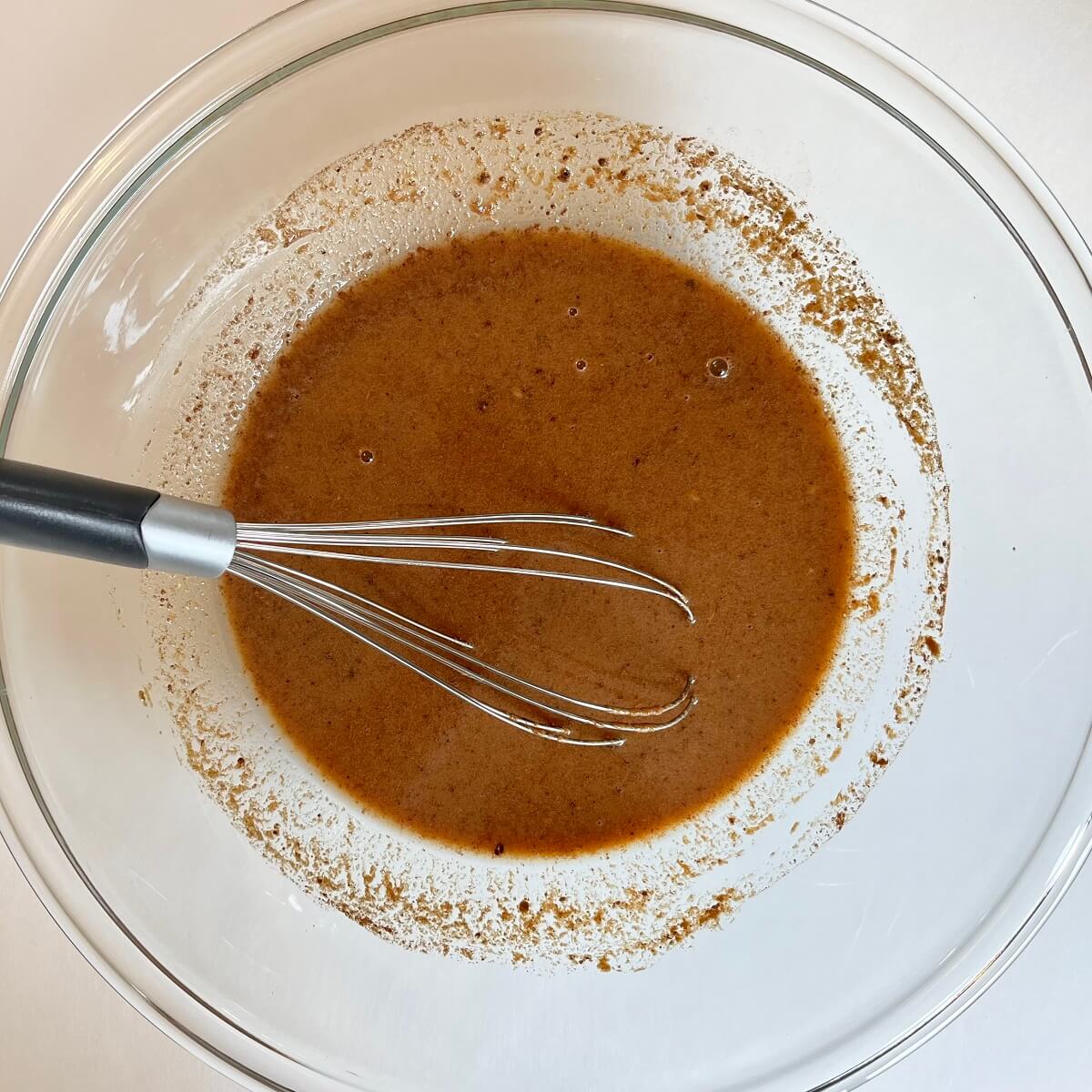 Wet ingredients for carrot cake in a glass bowl.