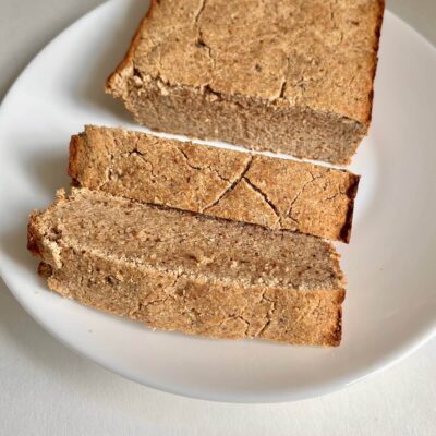 A loaf of coconut flour vegan banana bread with two thick slices cut.