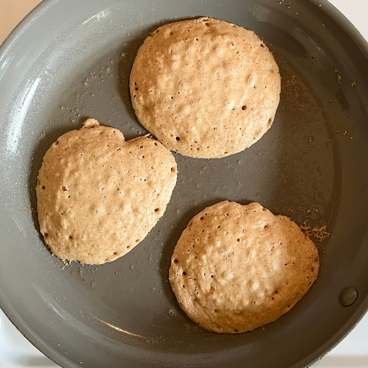 Pancakes cooking in a frying pan.