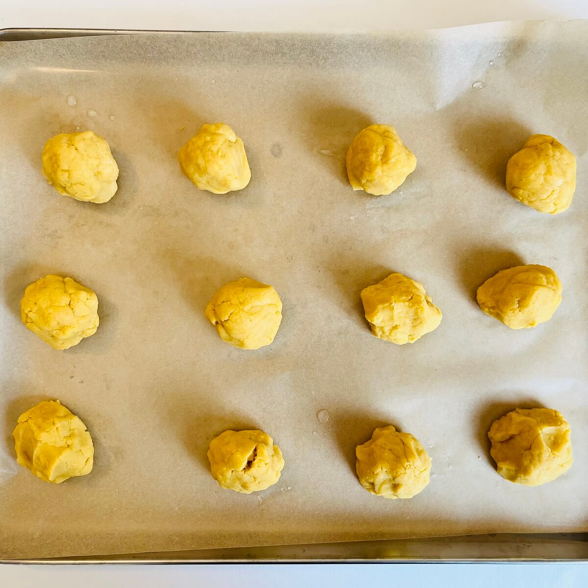 Corn cookie dough balls on a sheet pan.