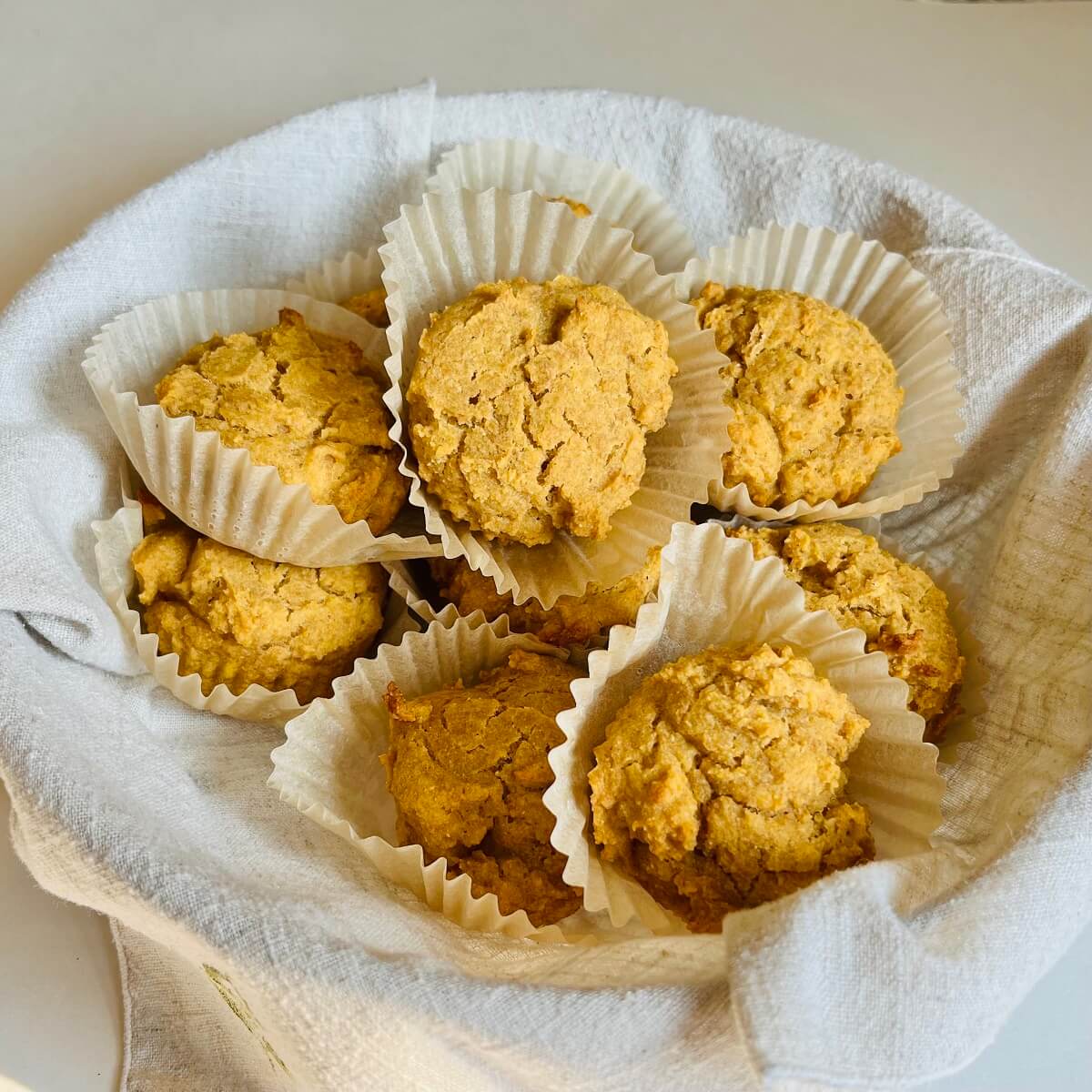 Corn flour muffins in a basket lined with a linen napkin.