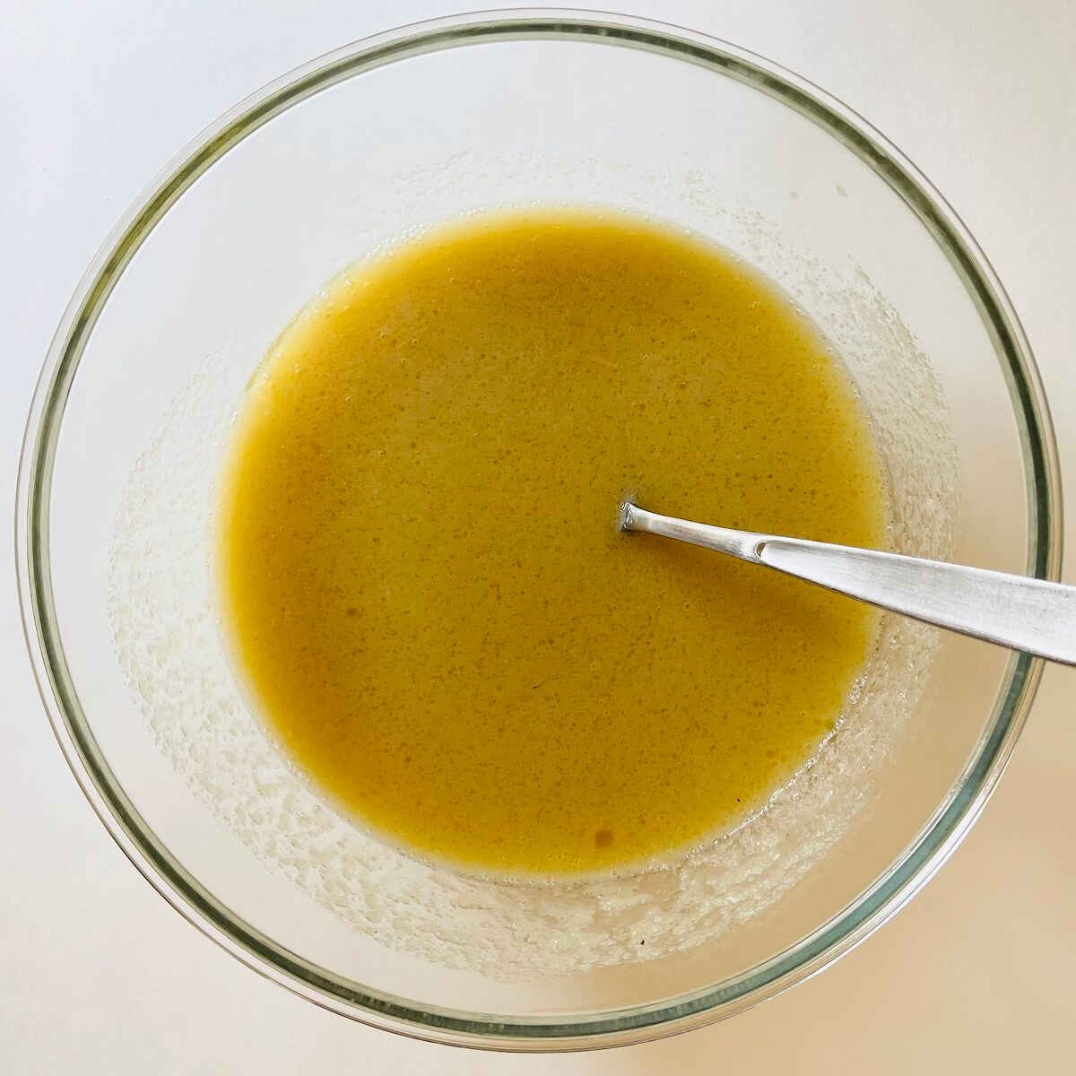 Wet ingredients for corn muffins in a glass bowl.