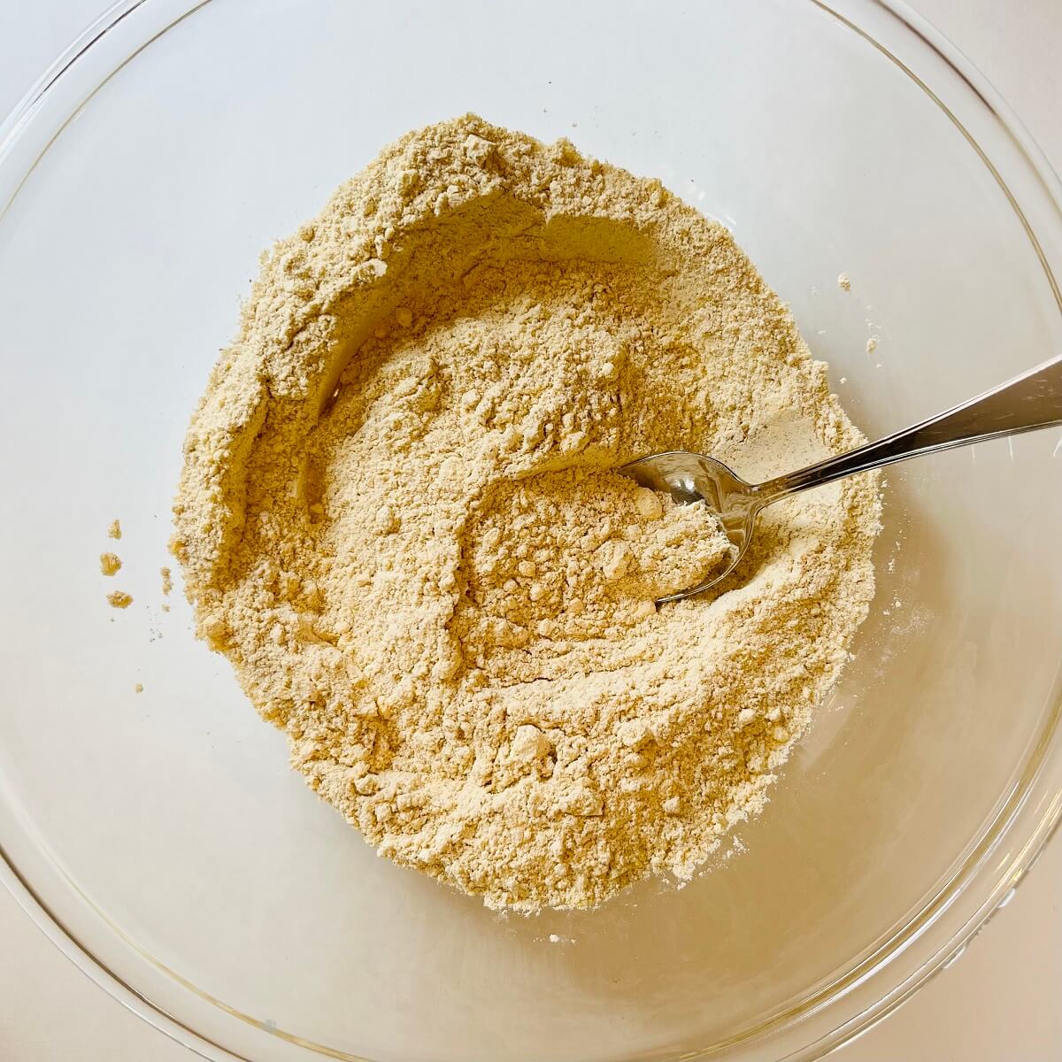 Dry ingredients for corn muffins mixed together in a glass bowl.