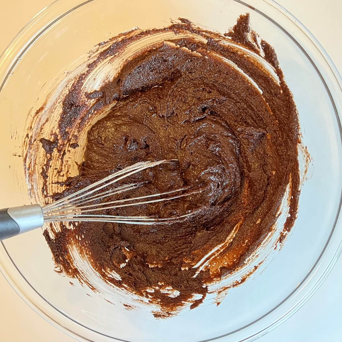 Vegan donut batter in a mixing bowl with a whisk.