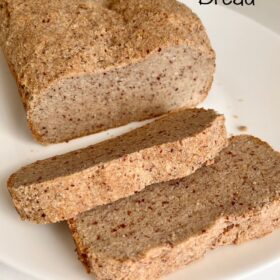 A rustic looking loaf of bread with two slices cut on a white platter.