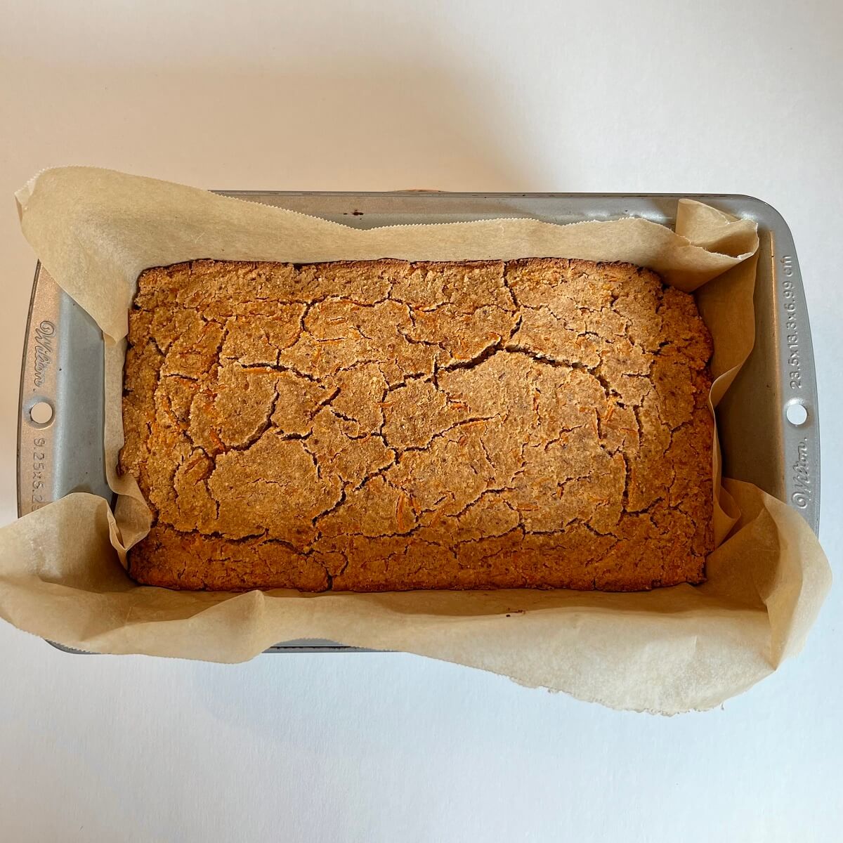 Freshly baked carrot cake in a loaf pan lined with parchment paper.