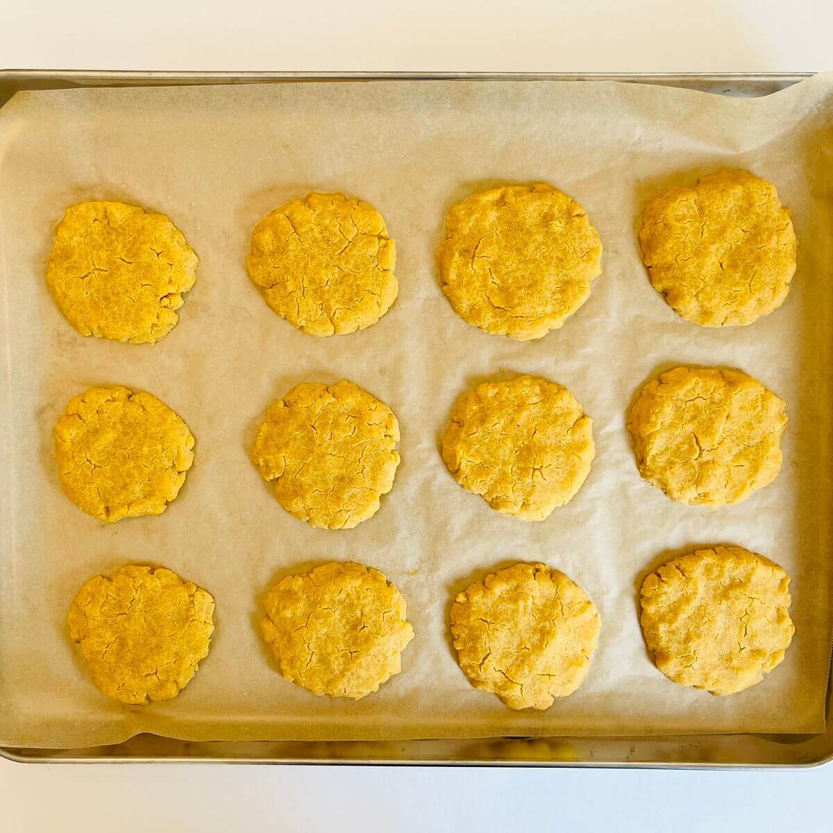 Freshly baked corn cookies on a sheet pan lined with parchment paper.