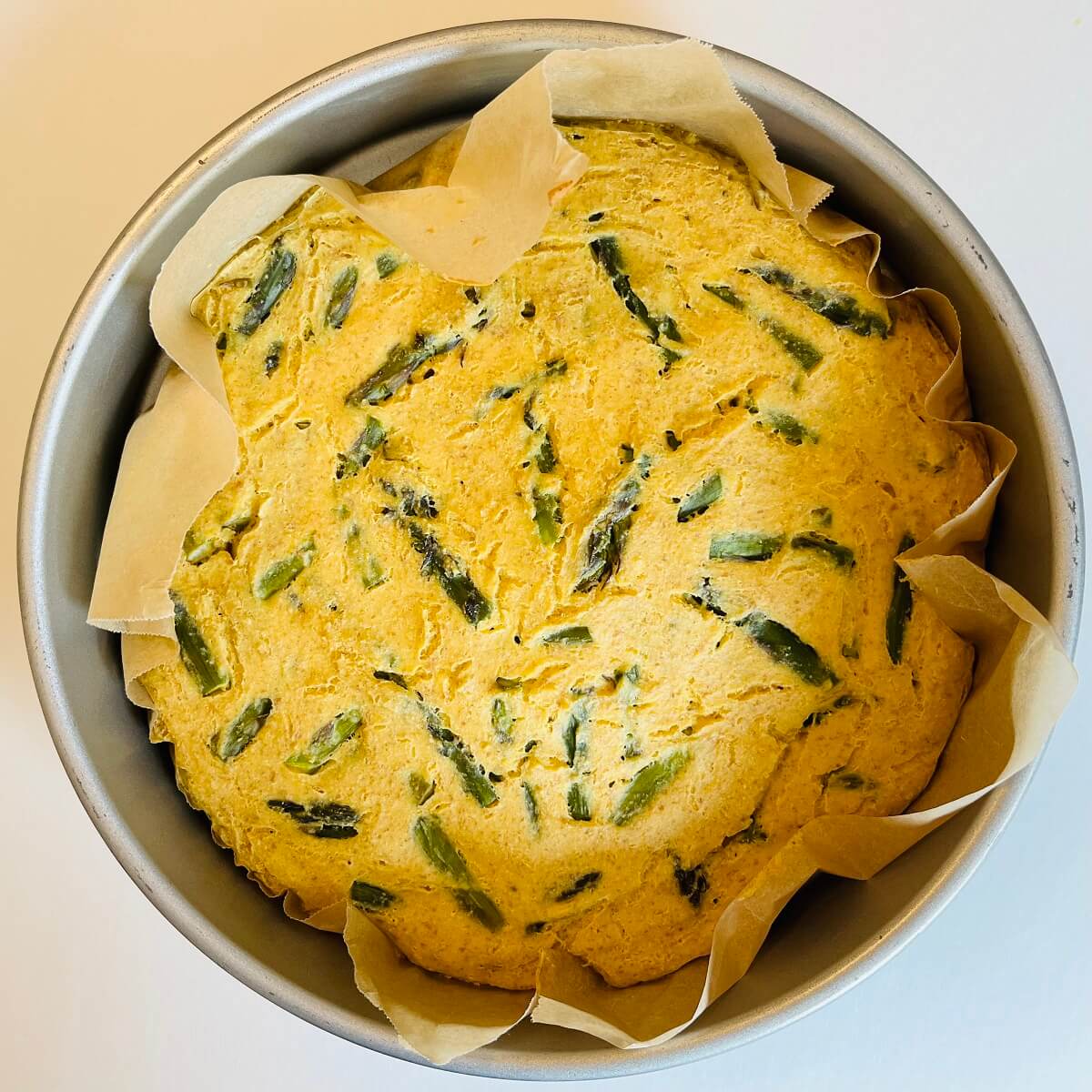 Freshly baked frittata in a baking pan lined with parchment paper.