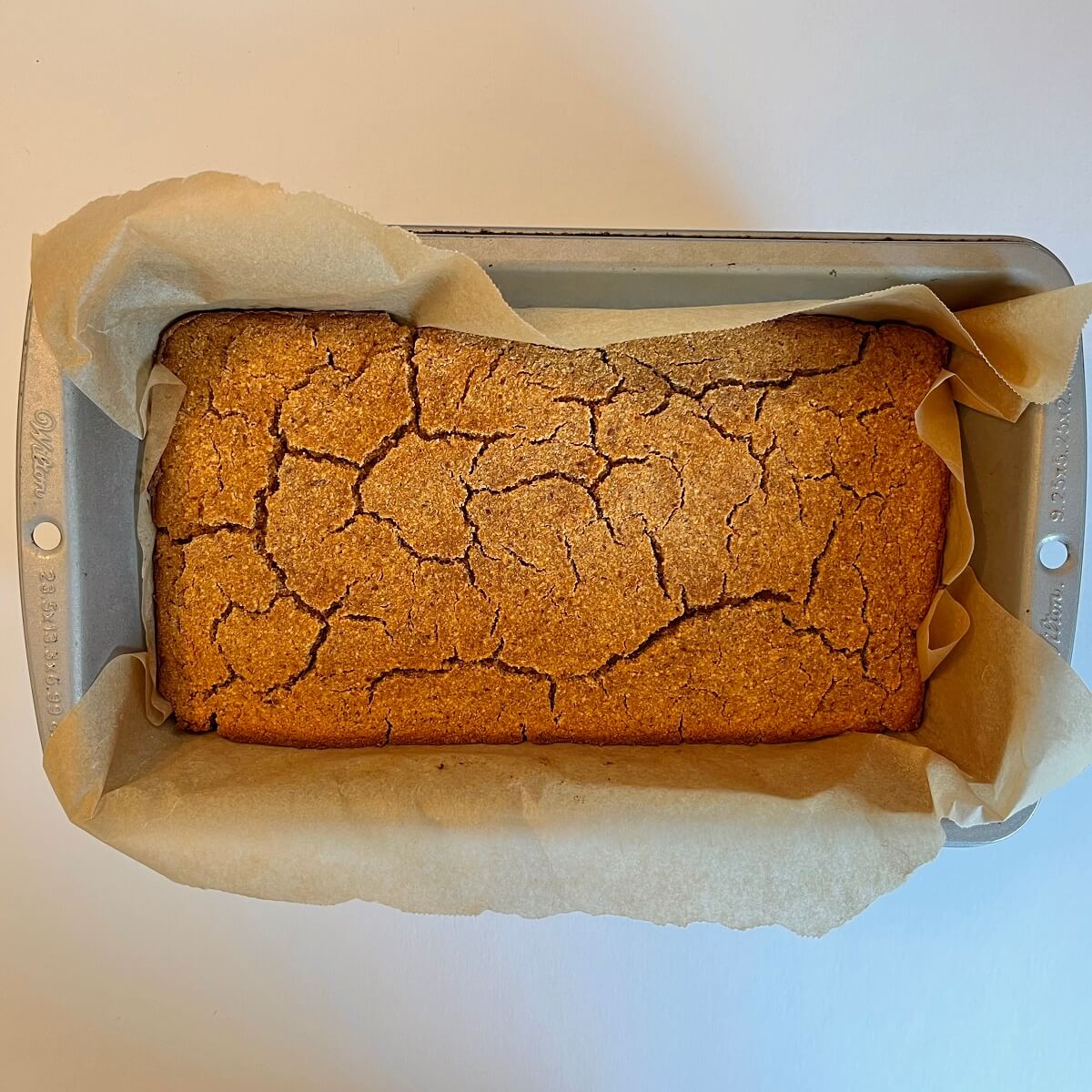 Freshly baked pumpkin bread in a loaf pan lined with parchment paper.
