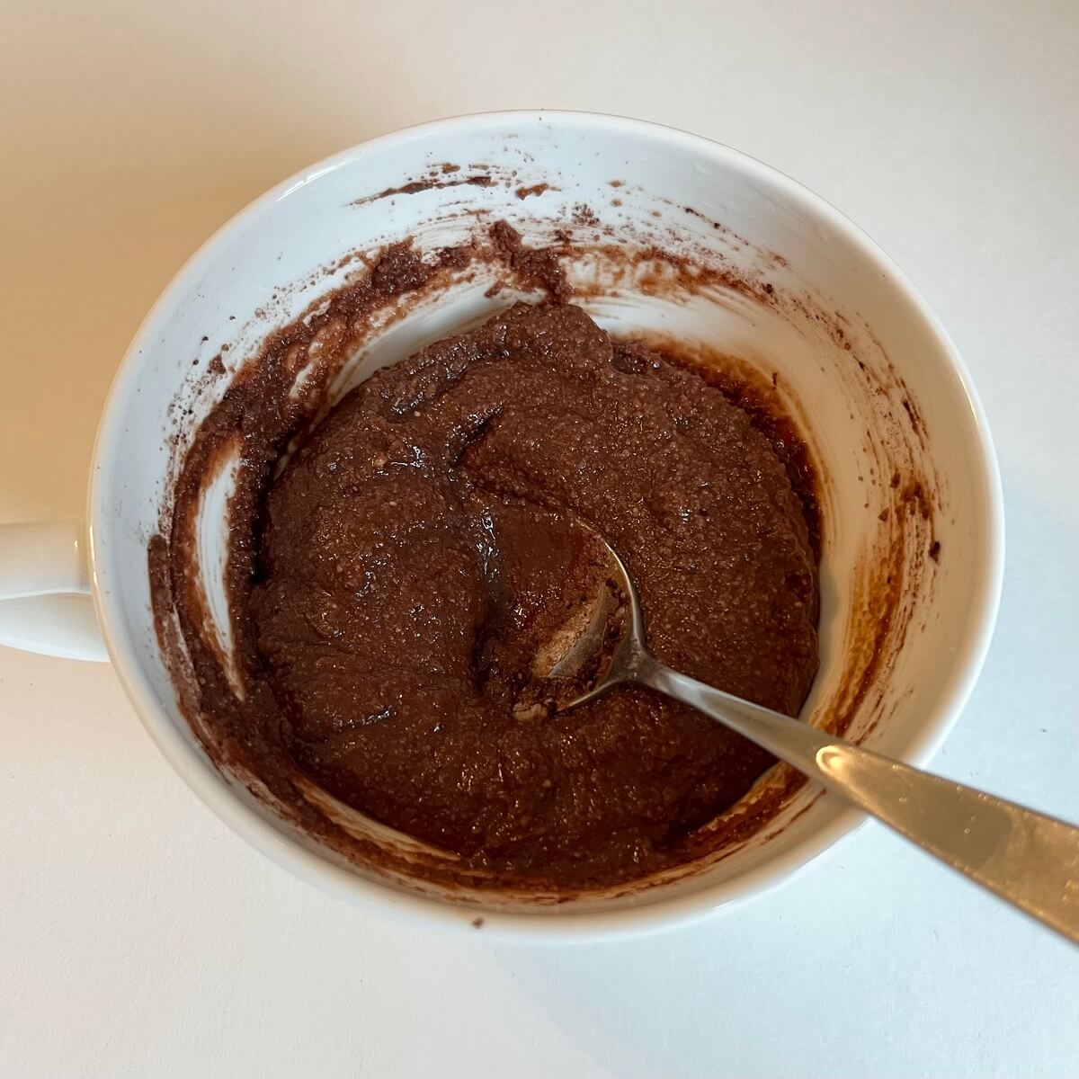 Chocolate cake batter in a white mug.