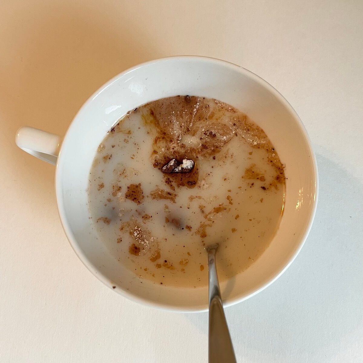 Ingredients for mug cake being stirred in a white mug.