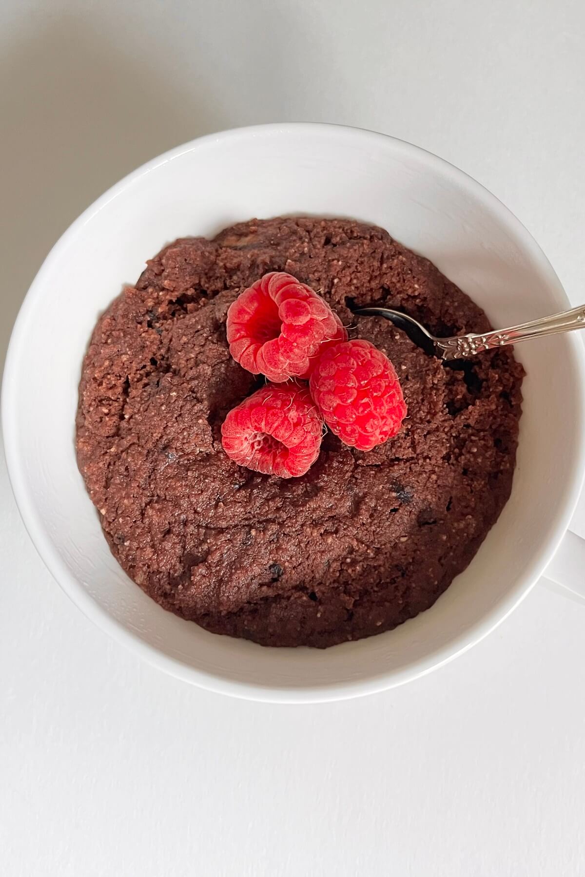 Paleo mug cake with raspberries on top.