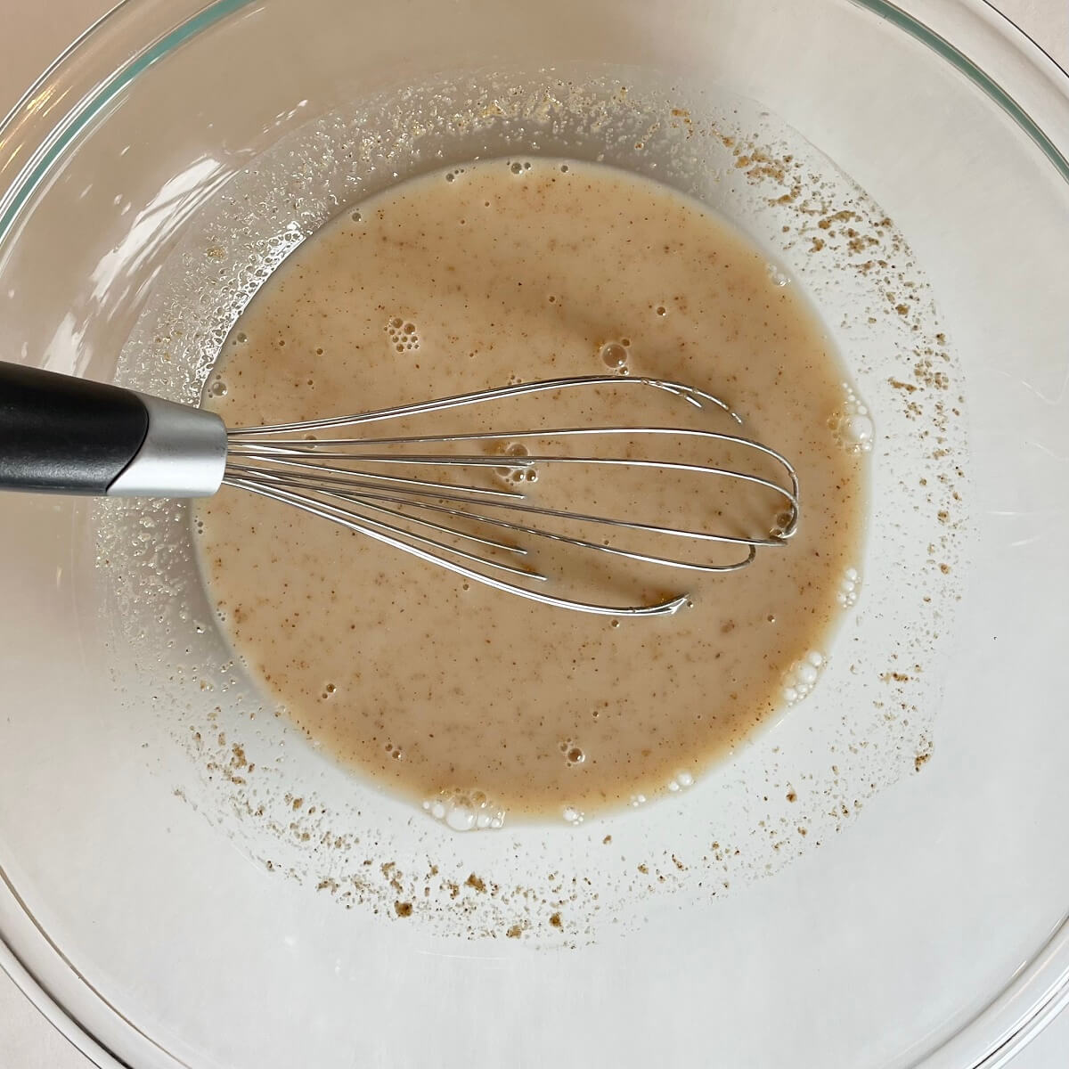 Wet ingredients for oat pancakes in a glass mixing bowl.