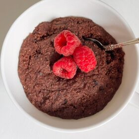 Chocolate mug cake garnished with fresh raspberries.