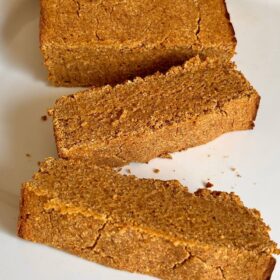 A loaf of pumpkin bread with two thick slices cut.
