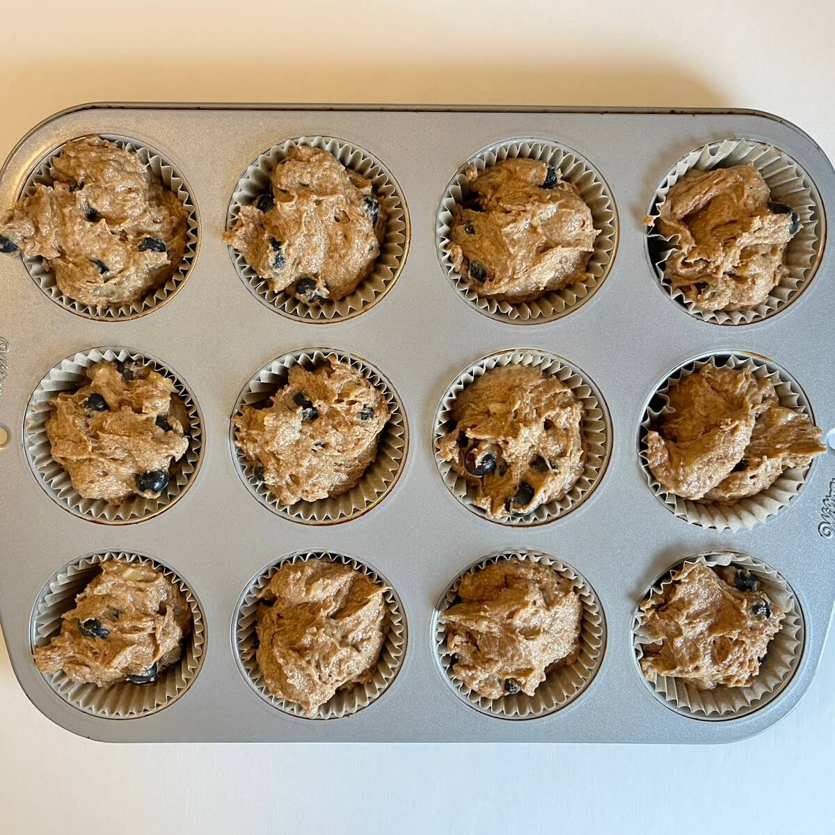 Raw blueberry muffins in a metal pan.