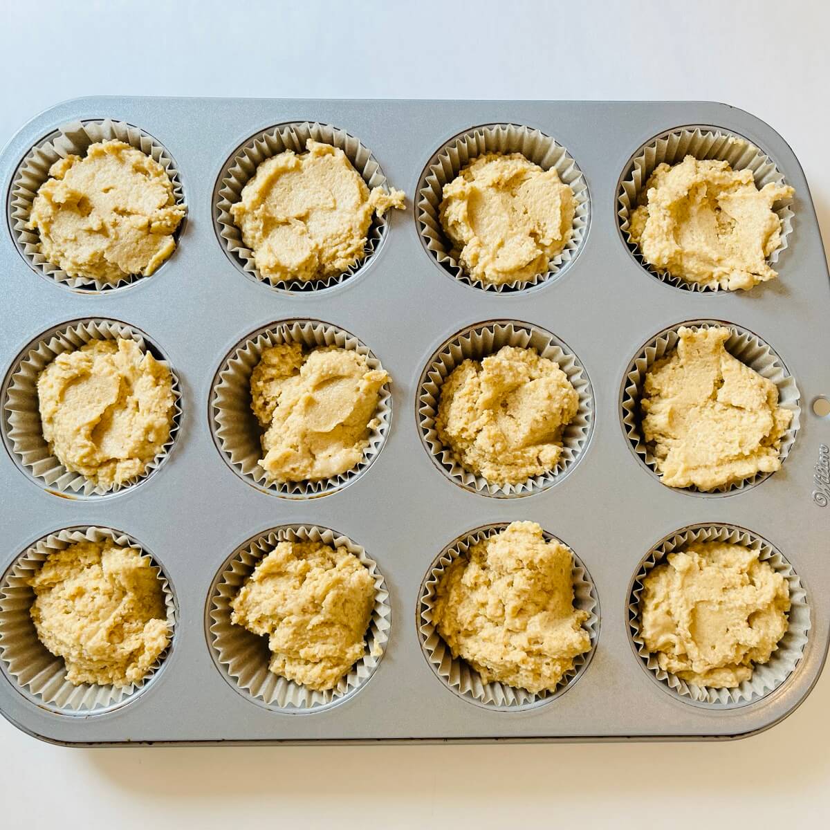 Raw corn muffins in a metal pan.