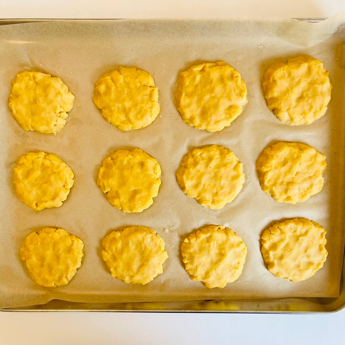 Raw cornbread cookies on a sheet pan.