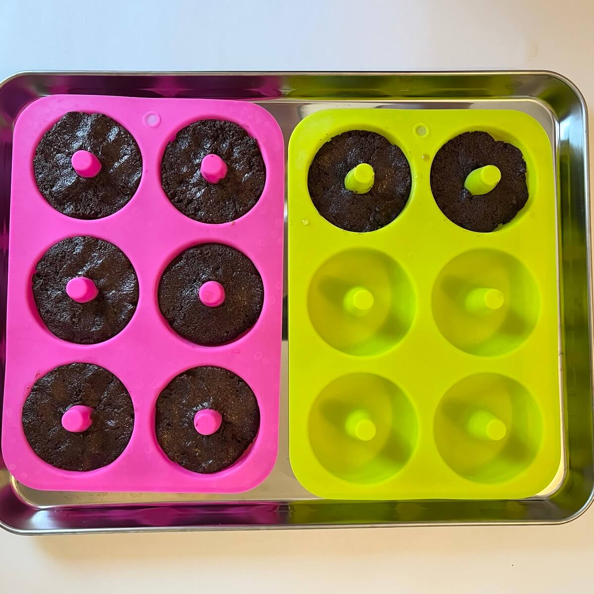Eight raw donuts in two silicone donut molds.