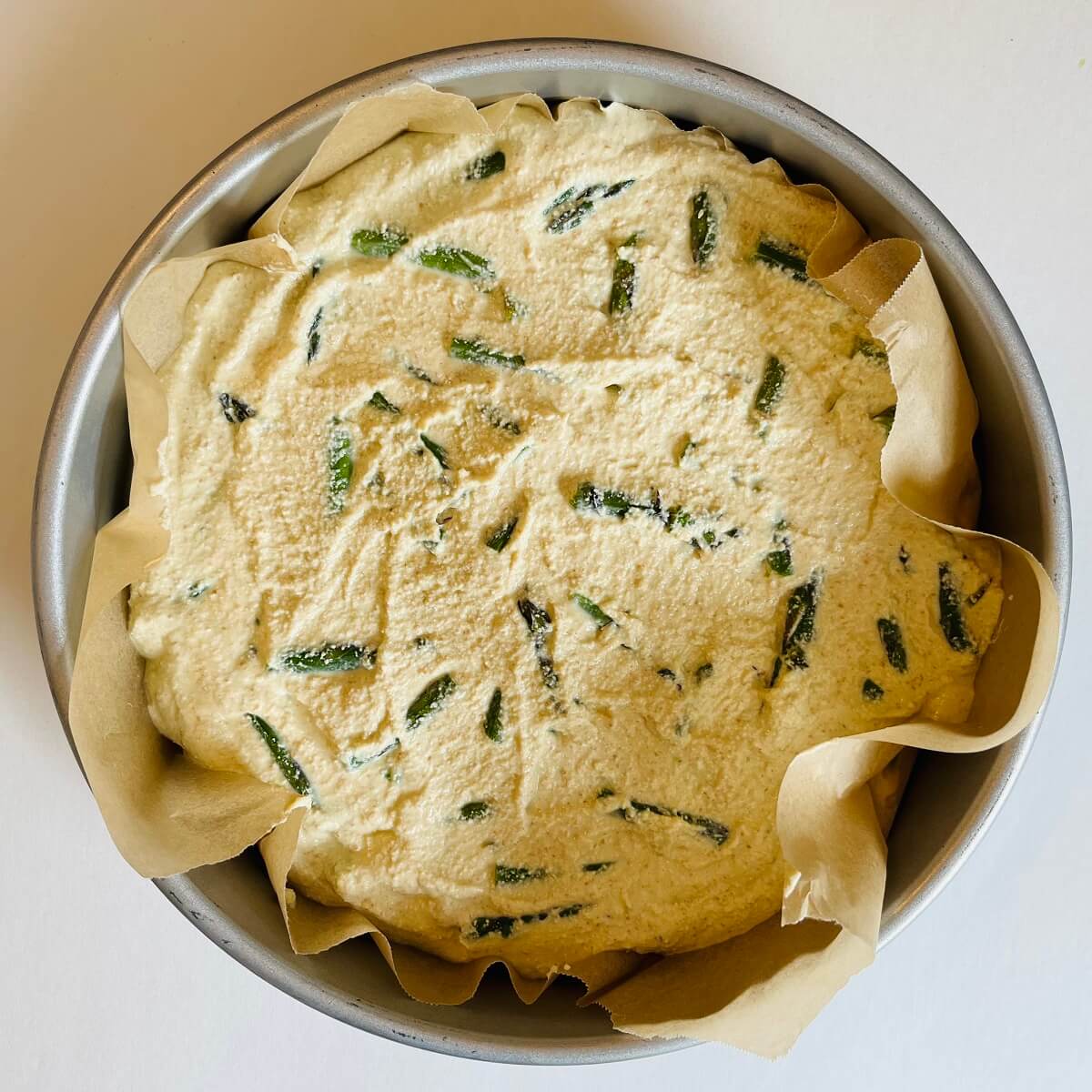 Raw frittata in a pan lined with parchment paper.