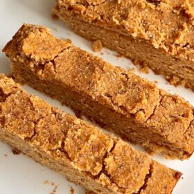 A loaf of sweet potato bread on a white plate with two slices cut.